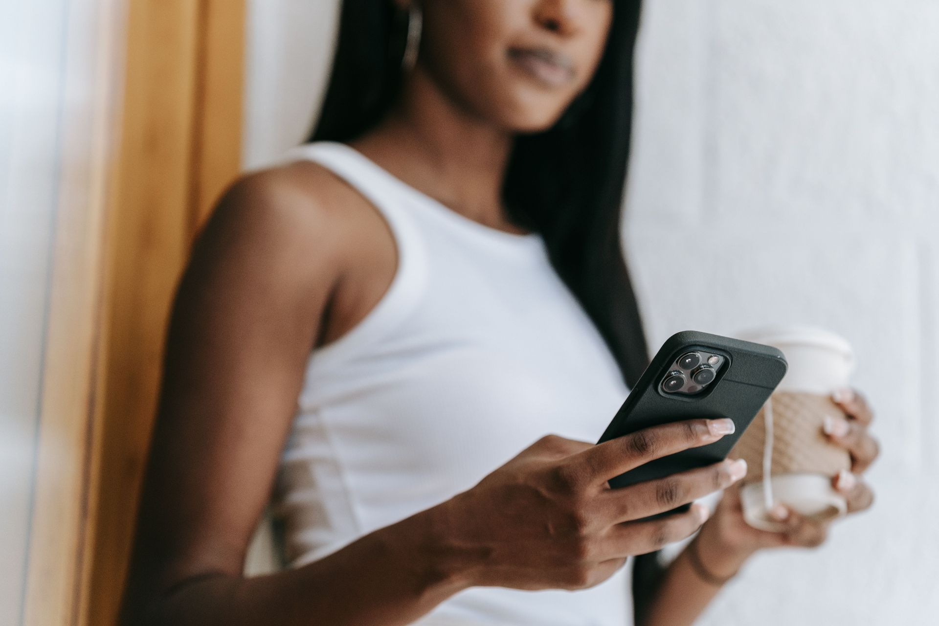 Parent checking phone while holding a coffee